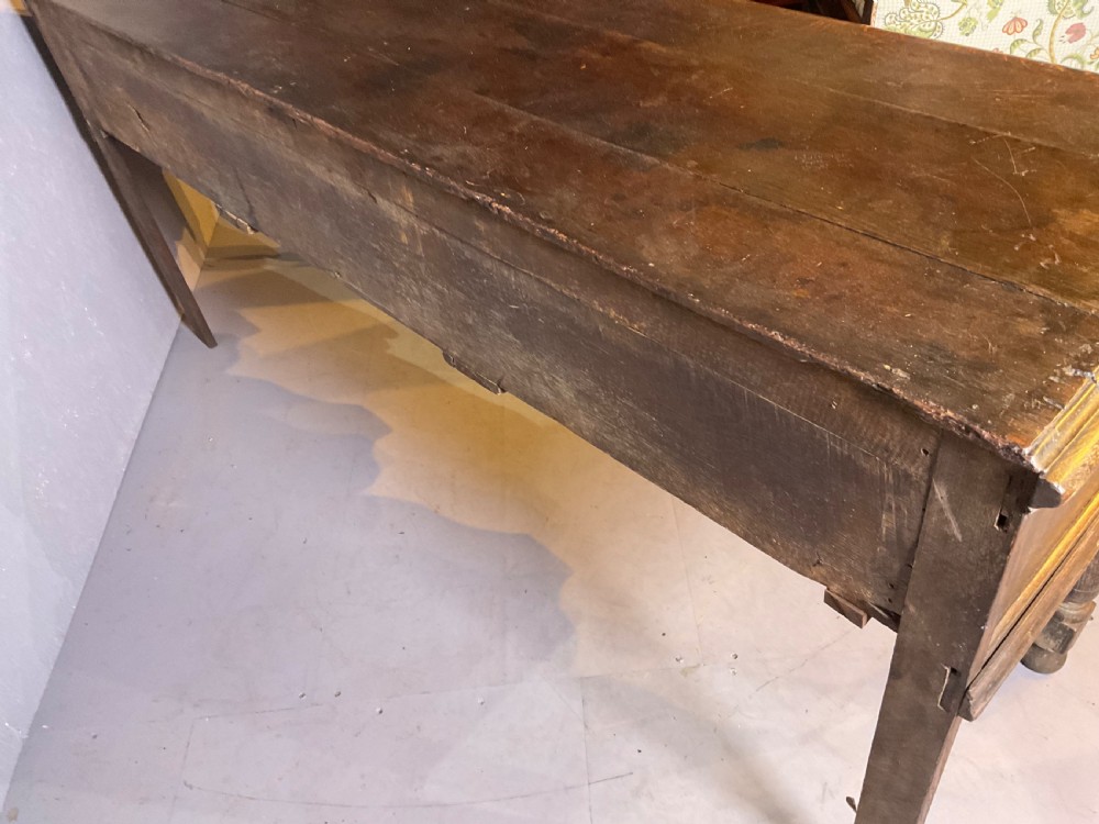 A late seventeenth-century dark oak serving dresser featuring three geometric moulded drawers with brass handles and a scalloped lower apron set on turned legs. View XIV