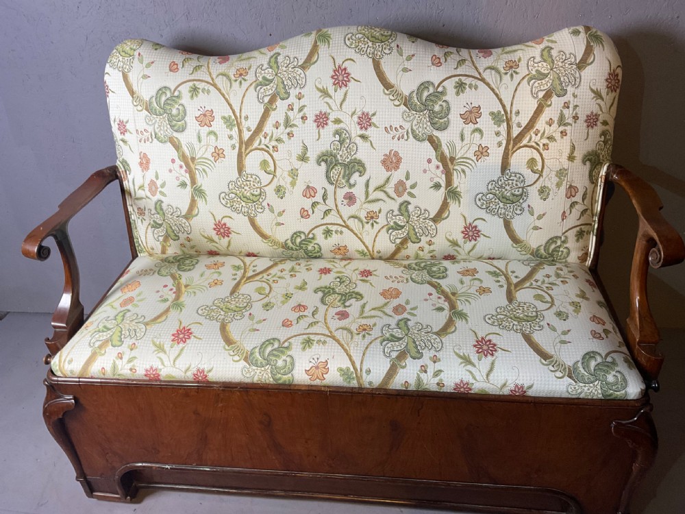 A Queen Anne style walnut settee featuring contoured wooden arms, a shaped upholstered backrest, and botanical floral pattern fabric. View II