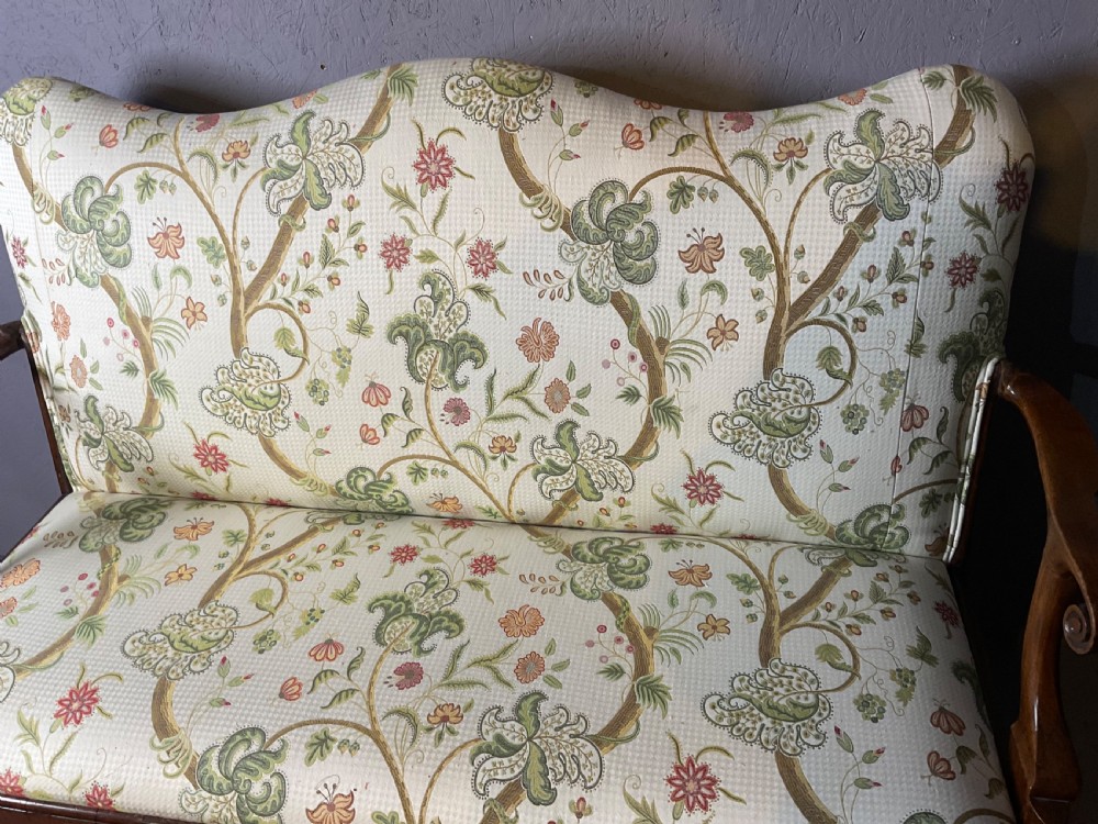 A Queen Anne style walnut settee featuring contoured wooden arms, a shaped upholstered backrest, and botanical floral pattern fabric. View III