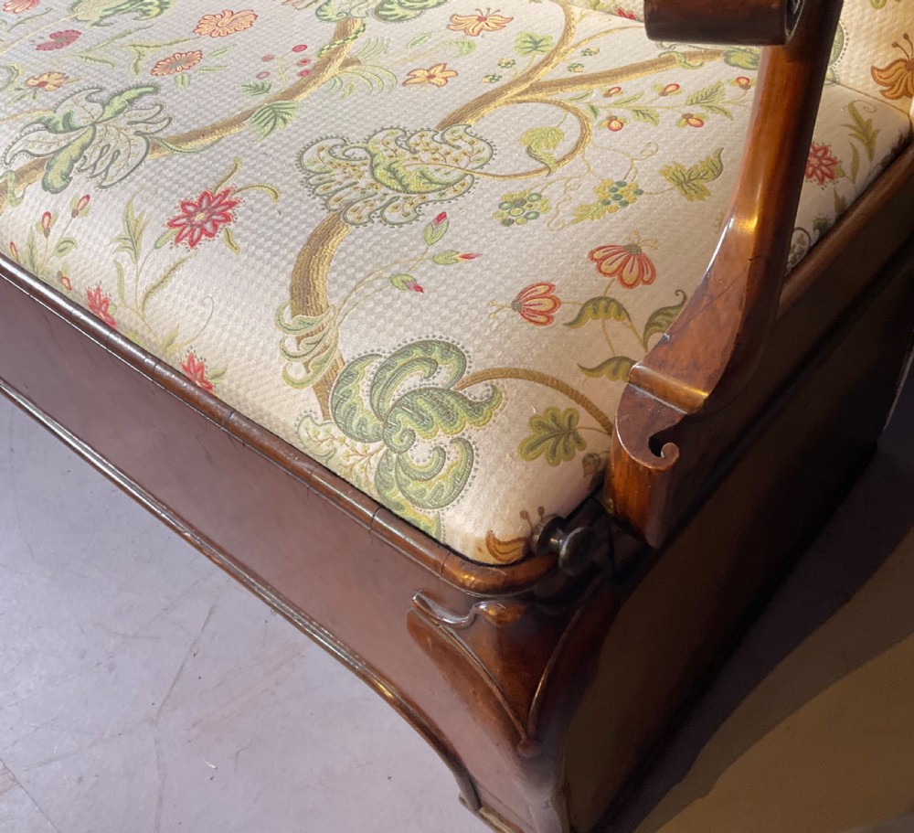 A Queen Anne style walnut settee featuring contoured wooden arms, a shaped upholstered backrest, and botanical floral pattern fabric. View IX