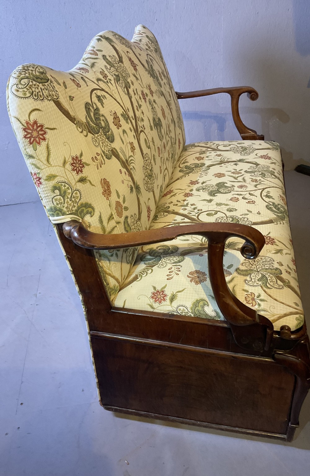 A Queen Anne style walnut settee featuring contoured wooden arms, a shaped upholstered backrest, and botanical floral pattern fabric. View XIV