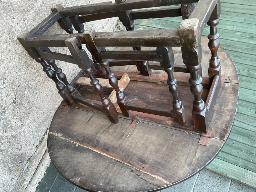 Underside view of a dark brown oak gateleg table showing baluster turned legs, stretchers, hand-forged iron hinges, and hinged drop leaves. View XXIV
