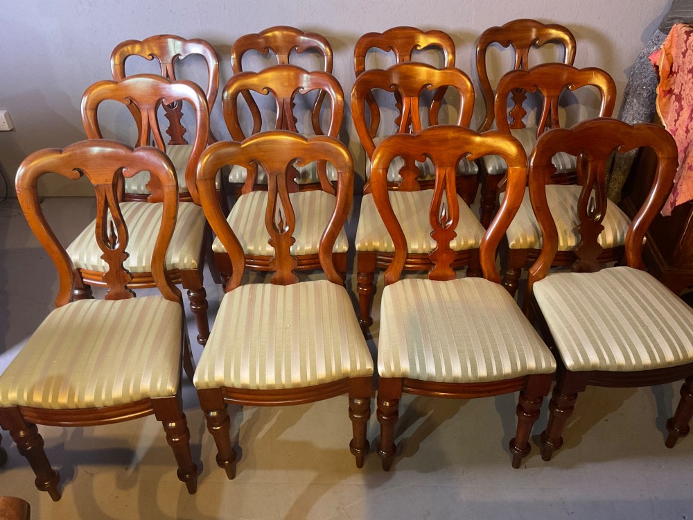 A set of twelve Victorian mahogany balloon back dining chairs featuring carved spear point splats and striped upholstered seats.
