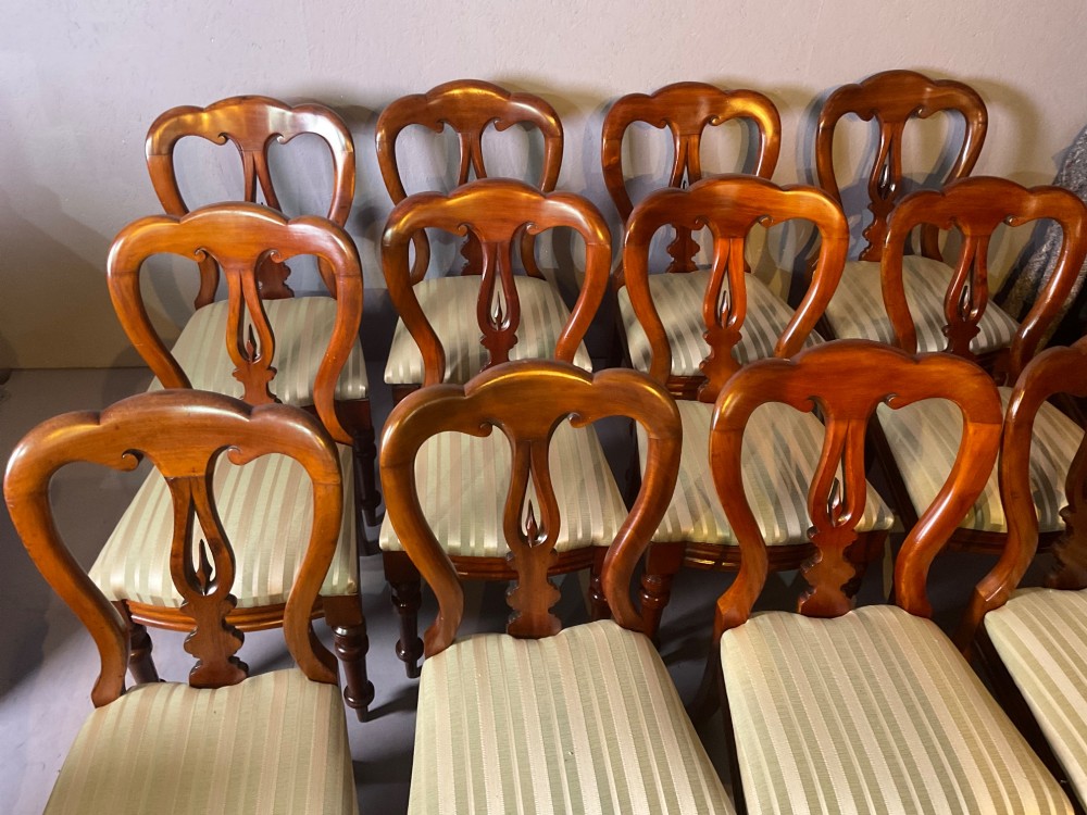 A set of twelve Victorian mahogany balloon back dining chairs featuring carved spear point splats and striped upholstered seats. View III
