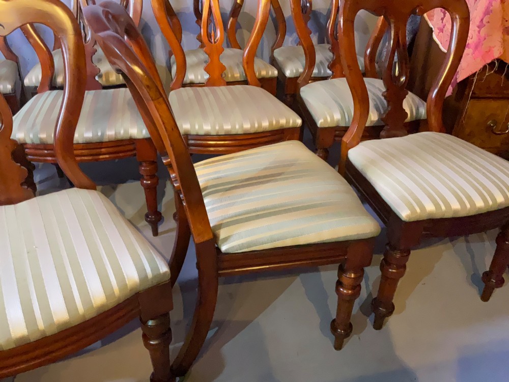 A set of twelve Victorian mahogany balloon back dining chairs featuring carved spear point splats and striped upholstered seats. View VII