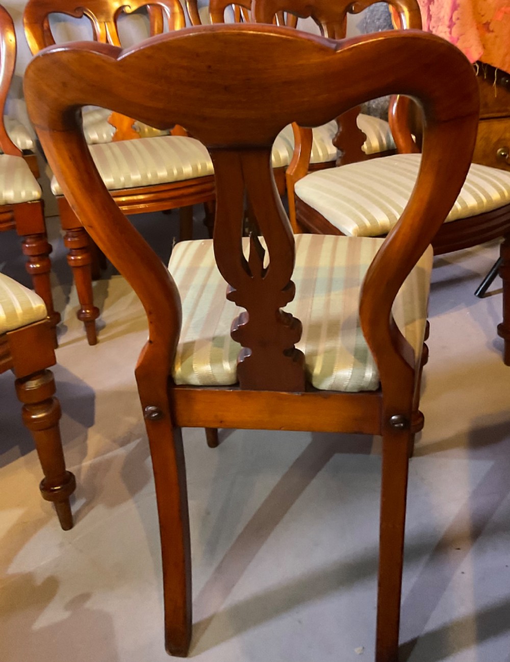 A set of twelve Victorian mahogany balloon back dining chairs featuring carved spear point splats and striped upholstered seats. View IX