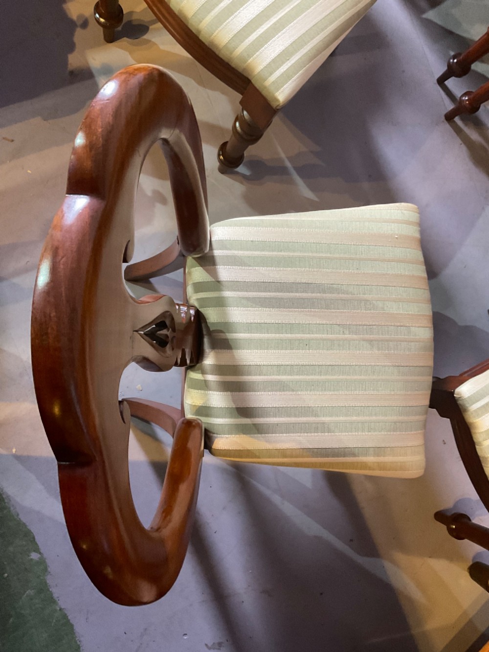 A set of twelve Victorian mahogany balloon back dining chairs featuring carved spear point splats and striped upholstered seats. View X