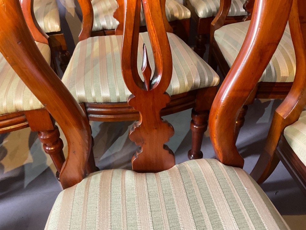 A set of twelve Victorian mahogany balloon back dining chairs featuring carved spear point splats and striped upholstered seats. View XII
