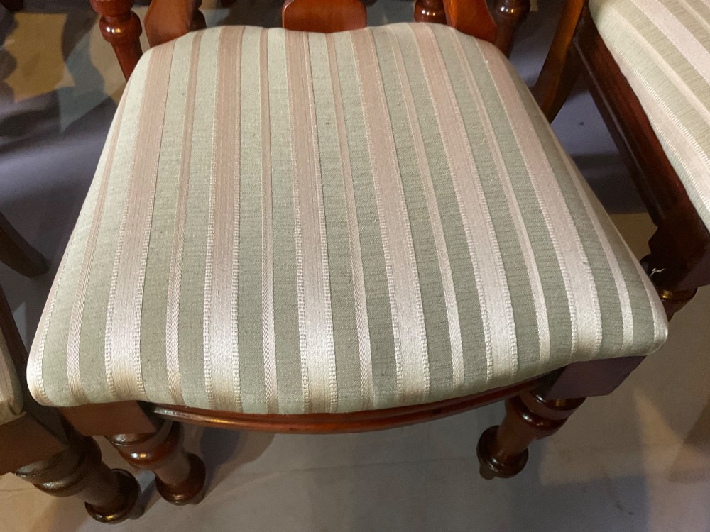 A set of twelve Victorian mahogany balloon back dining chairs featuring carved spear point splats and striped upholstered seats. View XIII