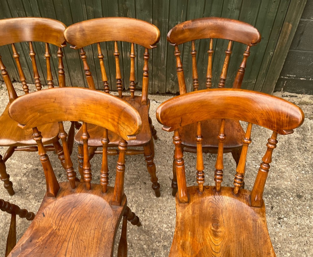 A set of six warm brown wooden dining chairs featuring spindle backrests, contoured wooden seats, and turned legs. View III