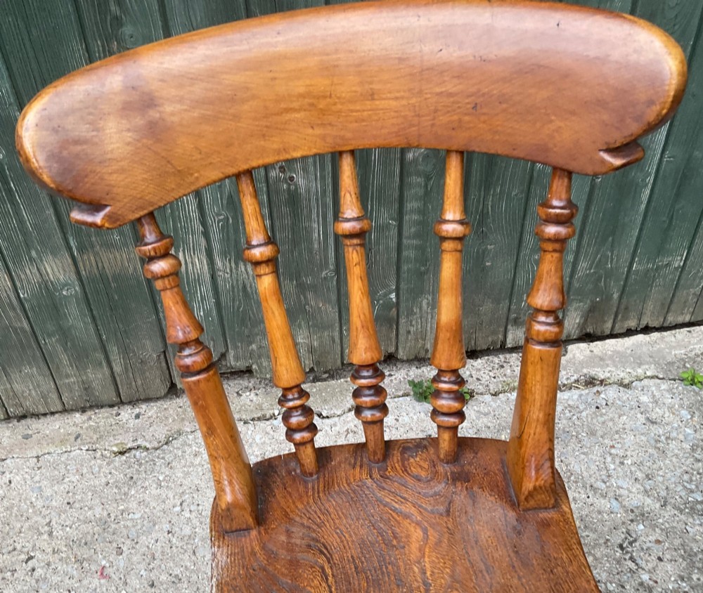 A set of six warm brown wooden dining chairs featuring spindle backrests, contoured wooden seats, and turned legs. View VIII