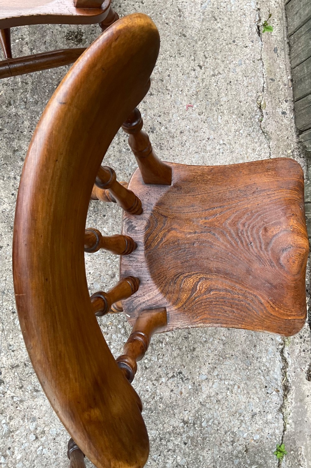 A set of six warm brown wooden dining chairs featuring spindle backrests, contoured wooden seats, and turned legs. View XII