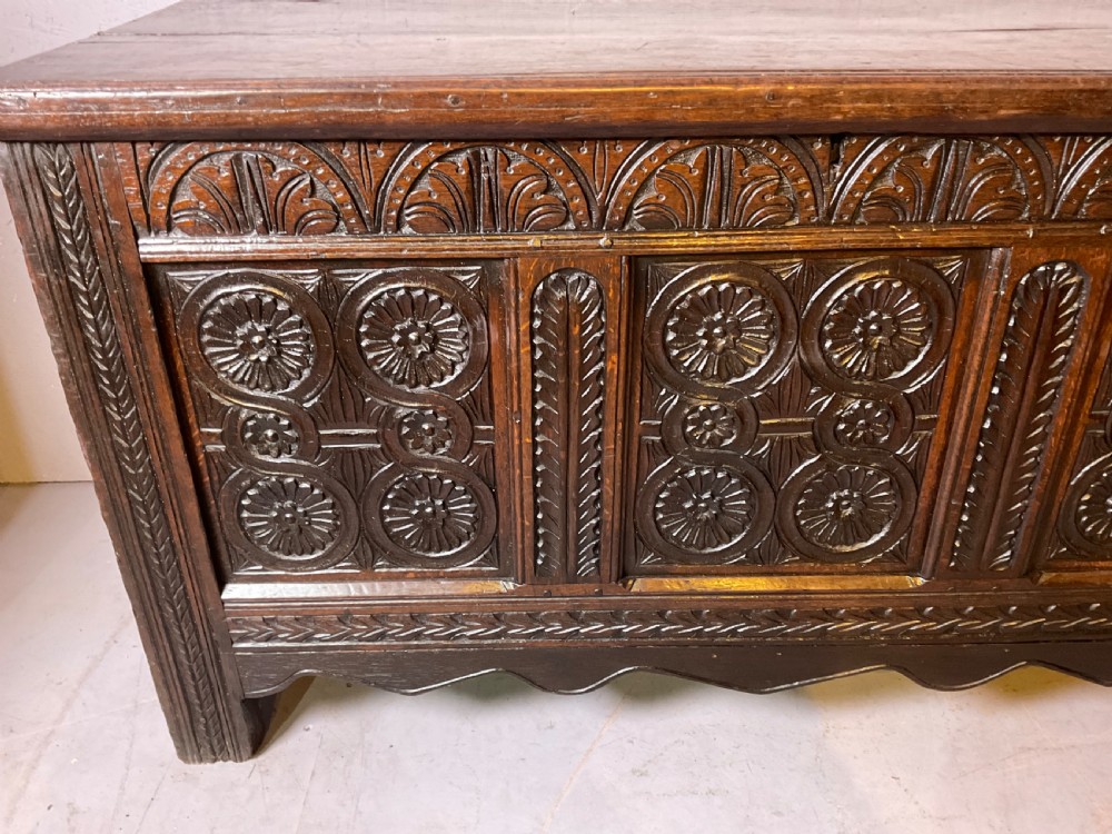 A seventeenth-century dark oak coffer featuring three relief-carved front panels with rosette motifs and a flat hinged lid. View III