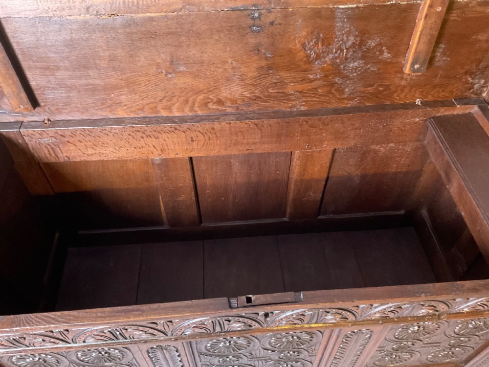 A seventeenth-century dark oak coffer featuring three relief-carved front panels with rosette motifs and a flat hinged lid. View VII