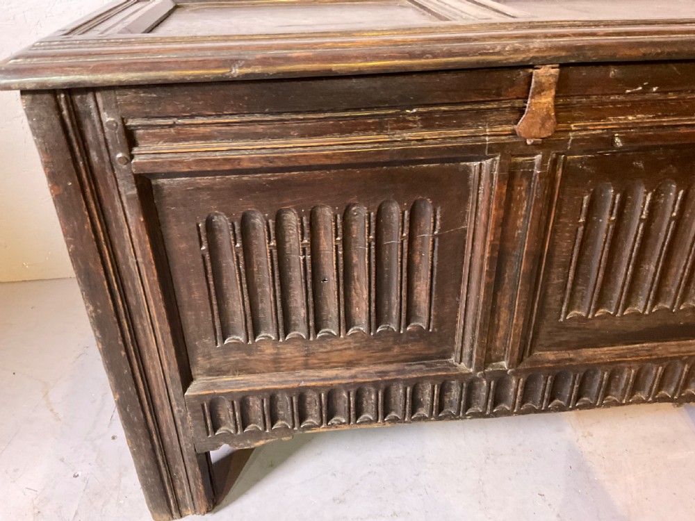 A dark oak 17th-century coffer featuring two carved linenfold front panels, a carved lower rail, and a framed hinged lid. View II
