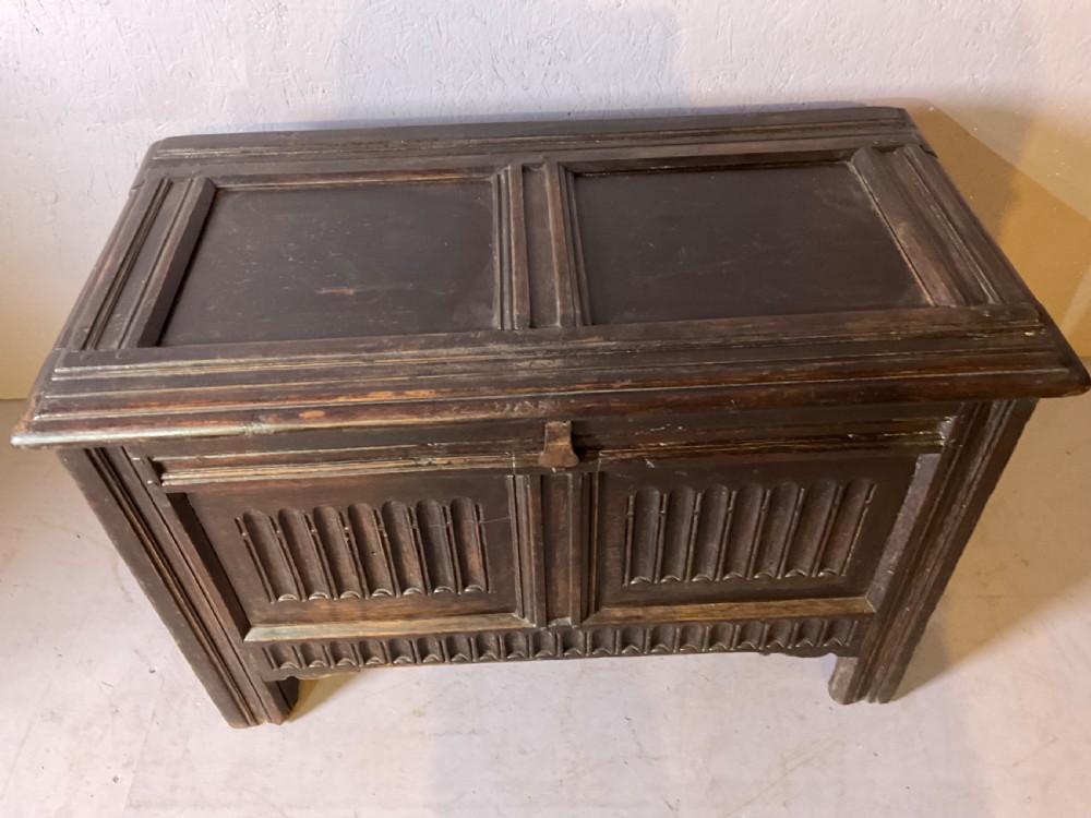 A dark oak 17th-century coffer featuring two carved linenfold front panels, a carved lower rail, and a framed hinged lid. View III