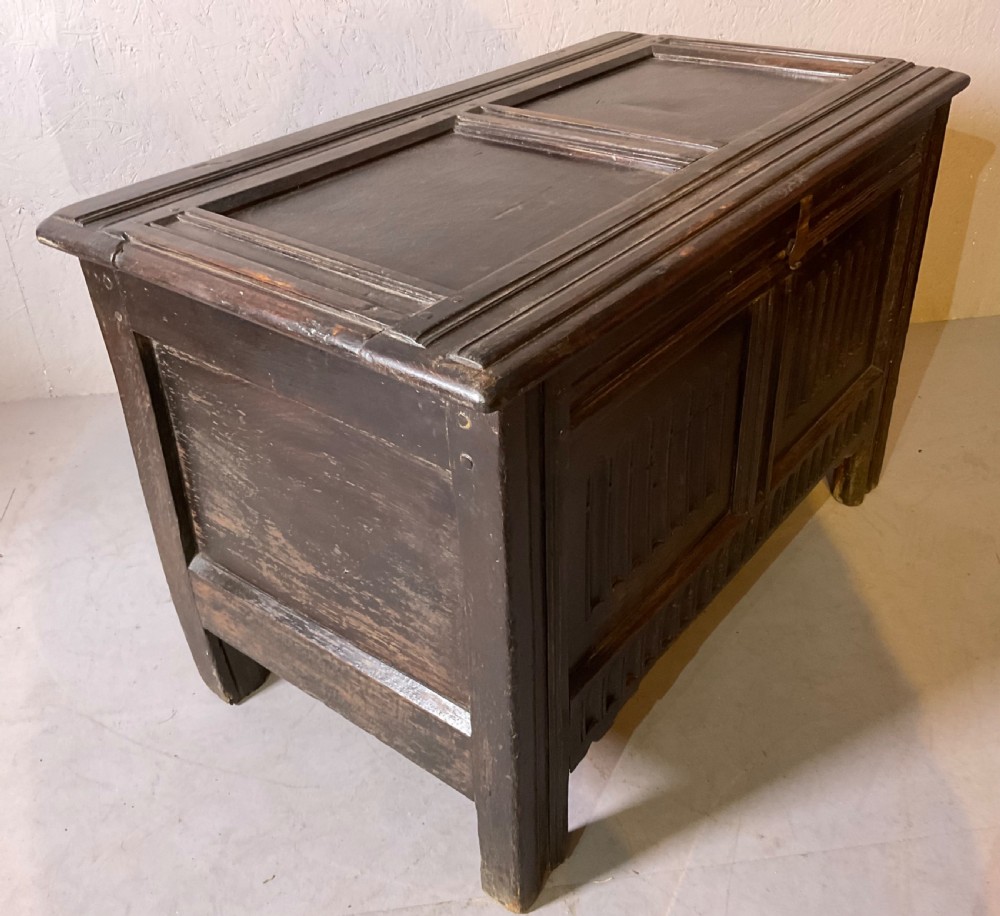 A dark oak 17th-century coffer featuring two carved linenfold front panels, a carved lower rail, and a framed hinged lid. View IV