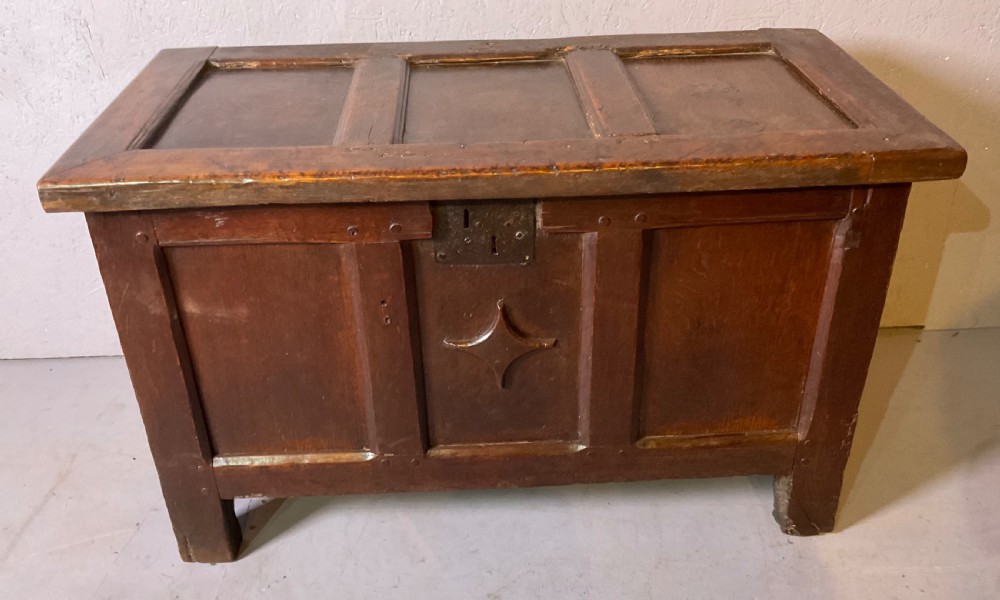 A 17th-century dark oak coffer featuring a three-panel front with a carved central star motif and an iron lockplate.