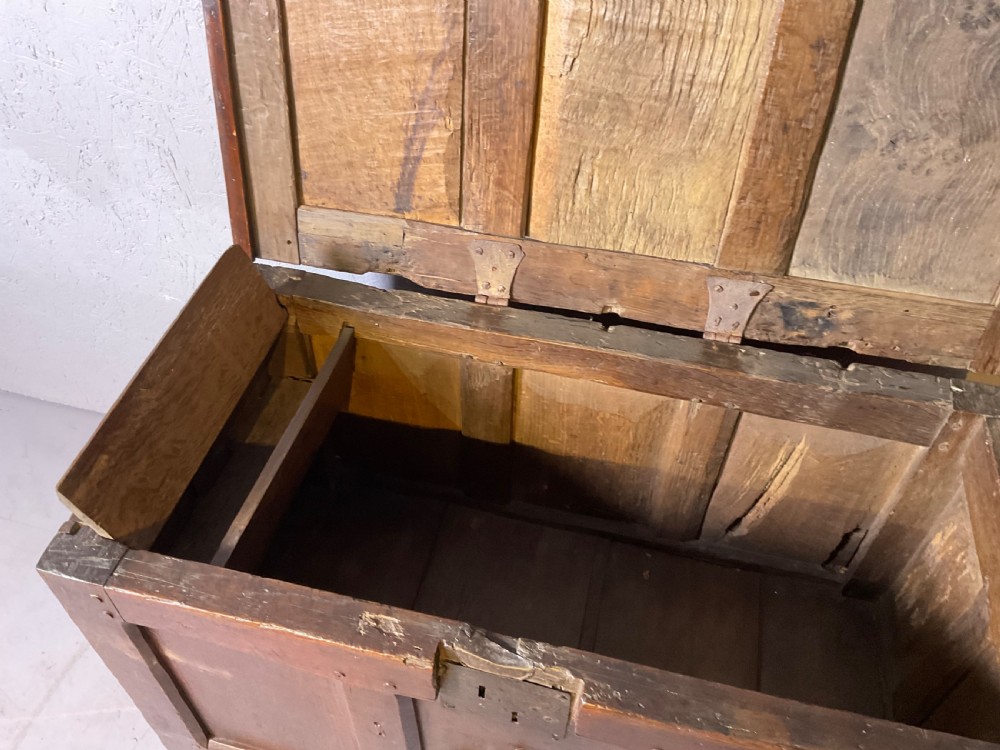 A 17th-century dark oak coffer featuring a three-panel front with a carved central star motif and an iron lockplate. View V