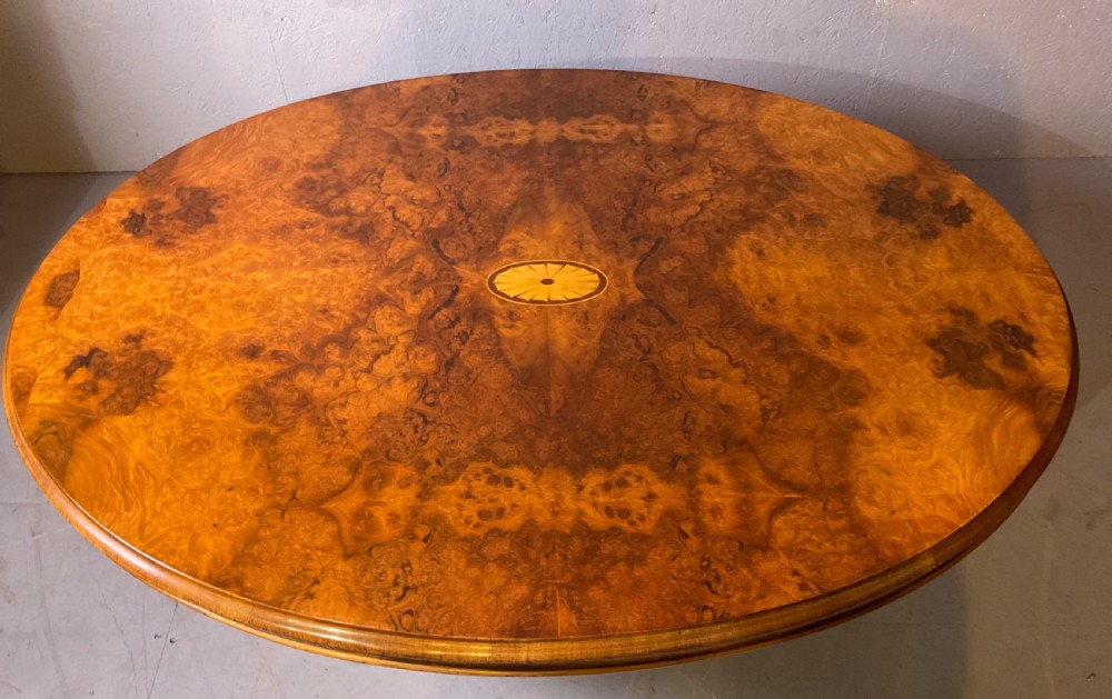 An oval burr walnut coffee table featuring central marquetry inlay, a moulded rim, and carved cabriole legs on brass castors. View II