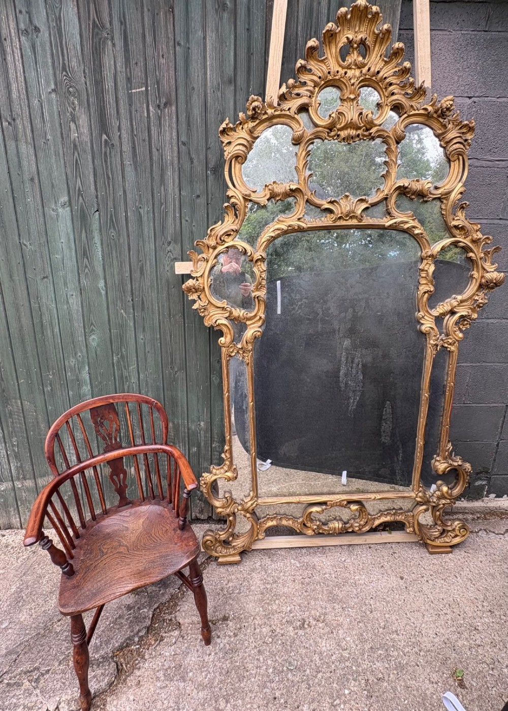 An ornate Georgian Rococo carved giltwood overmantel mirror featuring scrollwork, leaf motifs, and multi-pane glass panels.
