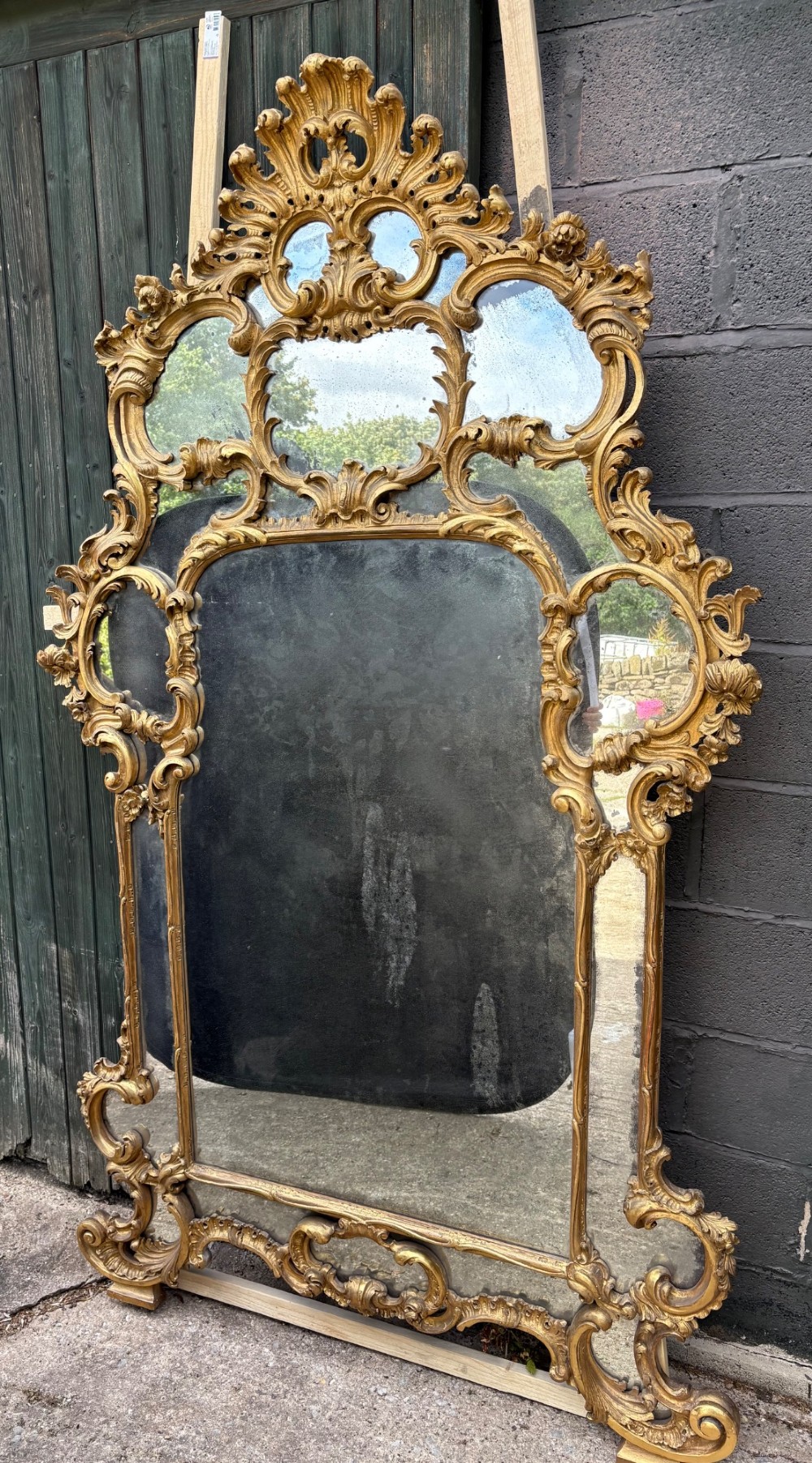 An ornate Georgian Rococo carved giltwood overmantel mirror featuring scrollwork, leaf motifs, and multi-pane glass panels. View II