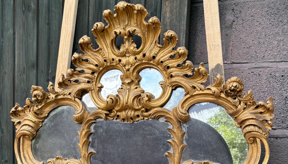 An ornate Georgian Rococo carved giltwood overmantel mirror featuring scrollwork, leaf motifs, and multi-pane glass panels. View IV