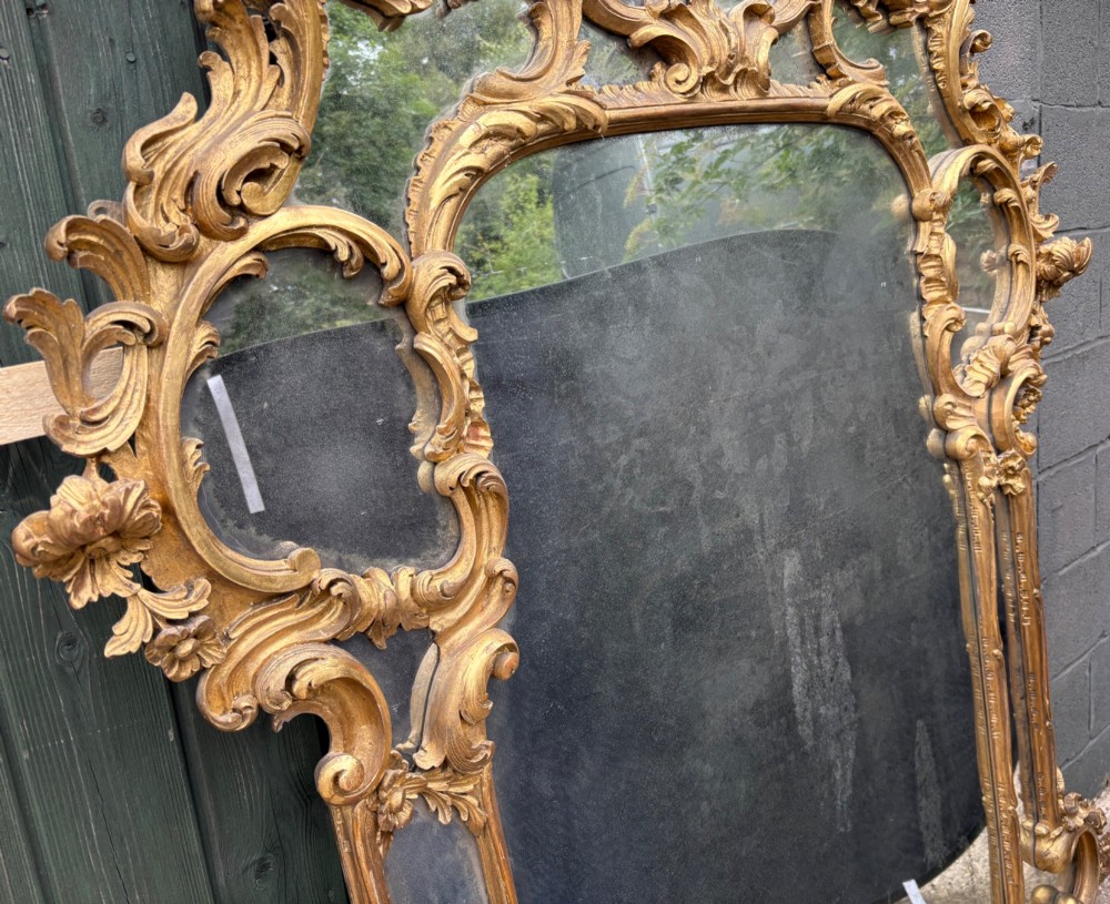 An ornate Georgian Rococo carved giltwood overmantel mirror featuring scrollwork, leaf motifs, and multi-pane glass panels. View IX