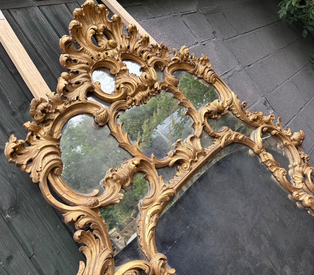 An ornate Georgian Rococo carved giltwood overmantel mirror featuring scrollwork, leaf motifs, and multi-pane glass panels. View X