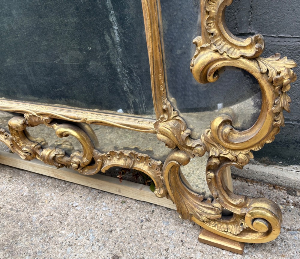 An ornate Georgian Rococo carved giltwood overmantel mirror featuring scrollwork, leaf motifs, and multi-pane glass panels. View XIII