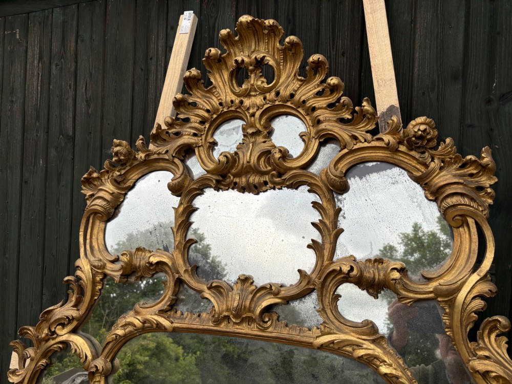An ornate Georgian Rococo carved giltwood overmantel mirror featuring scrollwork, leaf motifs, and multi-pane glass panels. View XV