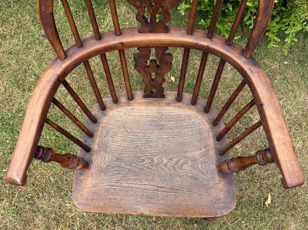 An antique yew wood low-back Windsor armchair featuring a pierced back splat, turned spindles, a contoured seat, and turned legs with a crinoline stretcher. View II