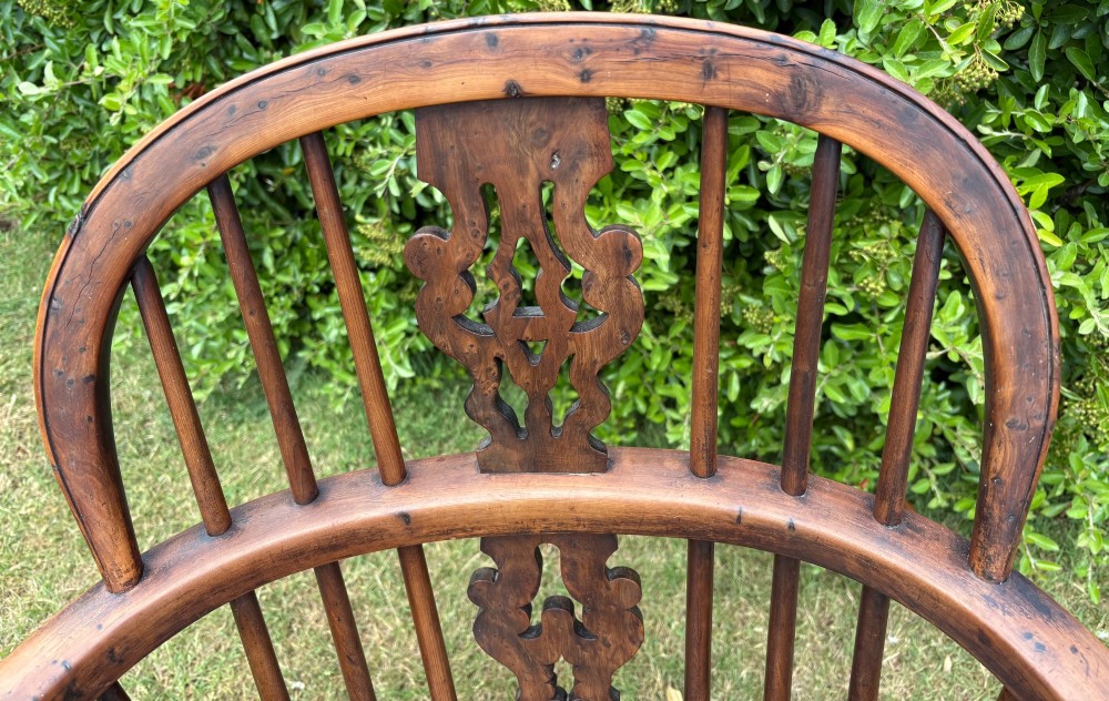 An antique yew wood low-back Windsor armchair featuring a pierced back splat, turned spindles, a contoured seat, and turned legs with a crinoline stretcher. View III