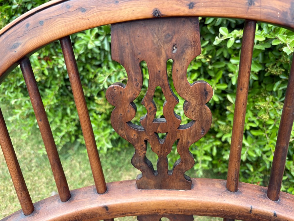 An antique yew wood low-back Windsor armchair featuring a pierced back splat, turned spindles, a contoured seat, and turned legs with a crinoline stretcher. View IV
