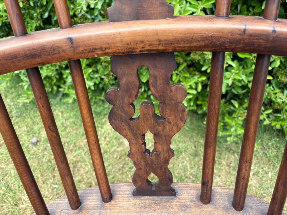 An antique yew wood low-back Windsor armchair featuring a pierced back splat, turned spindles, a contoured seat, and turned legs with a crinoline stretcher. View V
