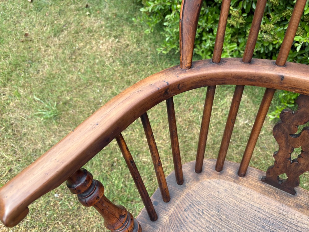An antique yew wood low-back Windsor armchair featuring a pierced back splat, turned spindles, a contoured seat, and turned legs with a crinoline stretcher. View VI