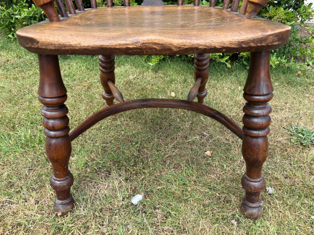An antique yew wood low-back Windsor armchair featuring a pierced back splat, turned spindles, a contoured seat, and turned legs with a crinoline stretcher. View VIII