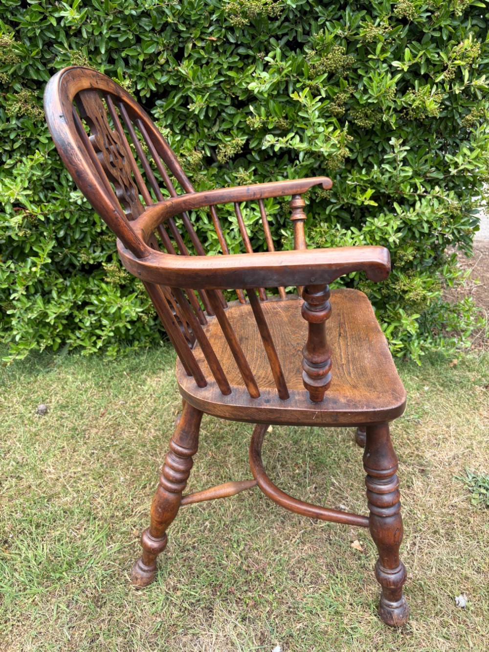 An antique yew wood low-back Windsor armchair featuring a pierced back splat, turned spindles, a contoured seat, and turned legs with a crinoline stretcher. View IX