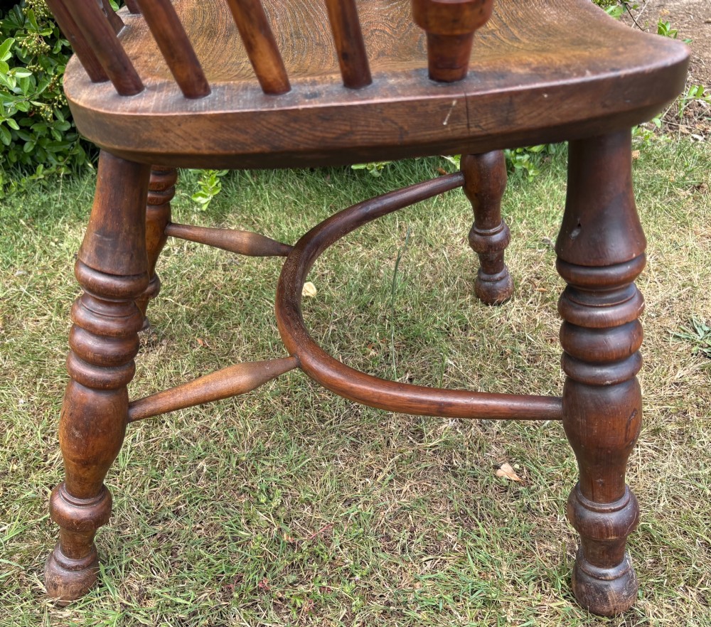 An antique yew wood low-back Windsor armchair featuring a pierced back splat, turned spindles, a contoured seat, and turned legs with a crinoline stretcher. View X