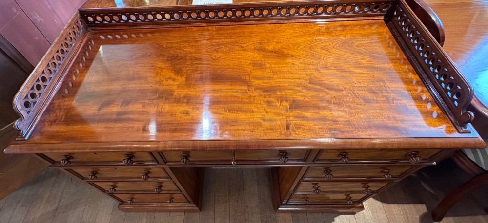 A nineteenth-century mahogany pedestal desk featuring nine drawers with turned wooden handles and a carved pierced gallery top. View III