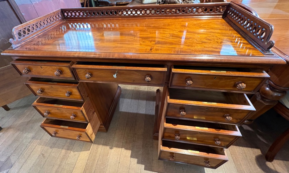 A nineteenth-century mahogany pedestal desk featuring nine drawers with turned wooden handles and a carved pierced gallery top. View V