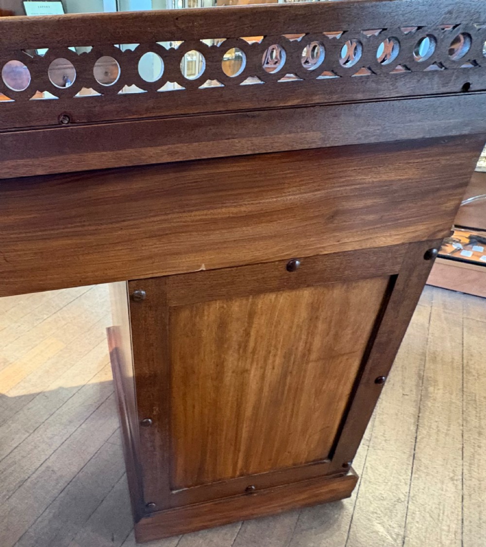 A nineteenth-century mahogany pedestal desk featuring nine drawers with turned wooden handles and a carved pierced gallery top. View VI