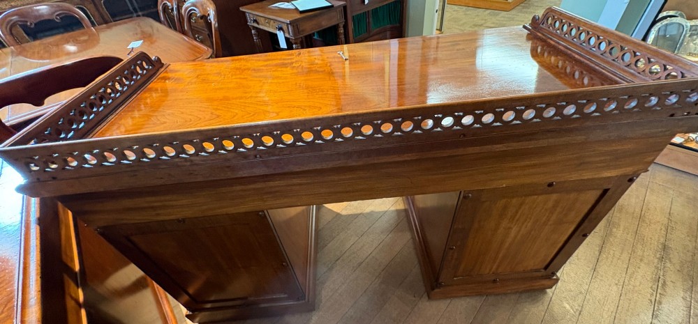 A nineteenth-century mahogany pedestal desk featuring nine drawers with turned wooden handles and a carved pierced gallery top. View IX