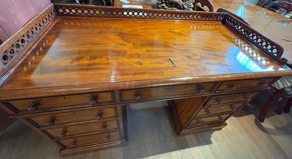 A nineteenth-century mahogany pedestal desk featuring nine drawers with turned wooden handles and a carved pierced gallery top. View XIII