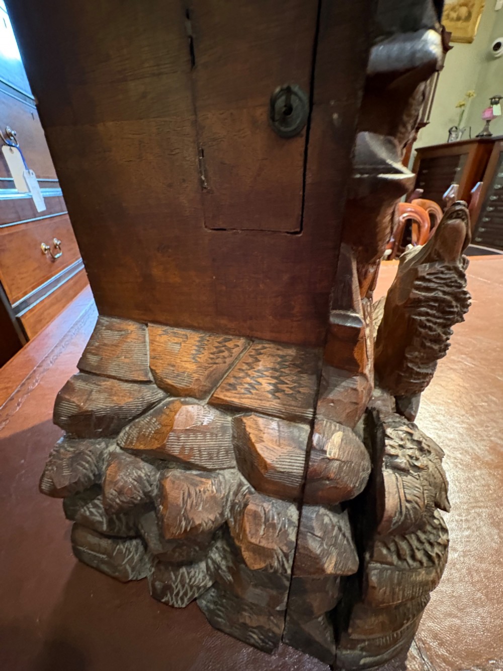 An intricately hand-carved dark wood Black Forest cuckoo clock featuring a bird atop a nest, a framed dial with Roman numerals, and a fox figure at the base. View IX
