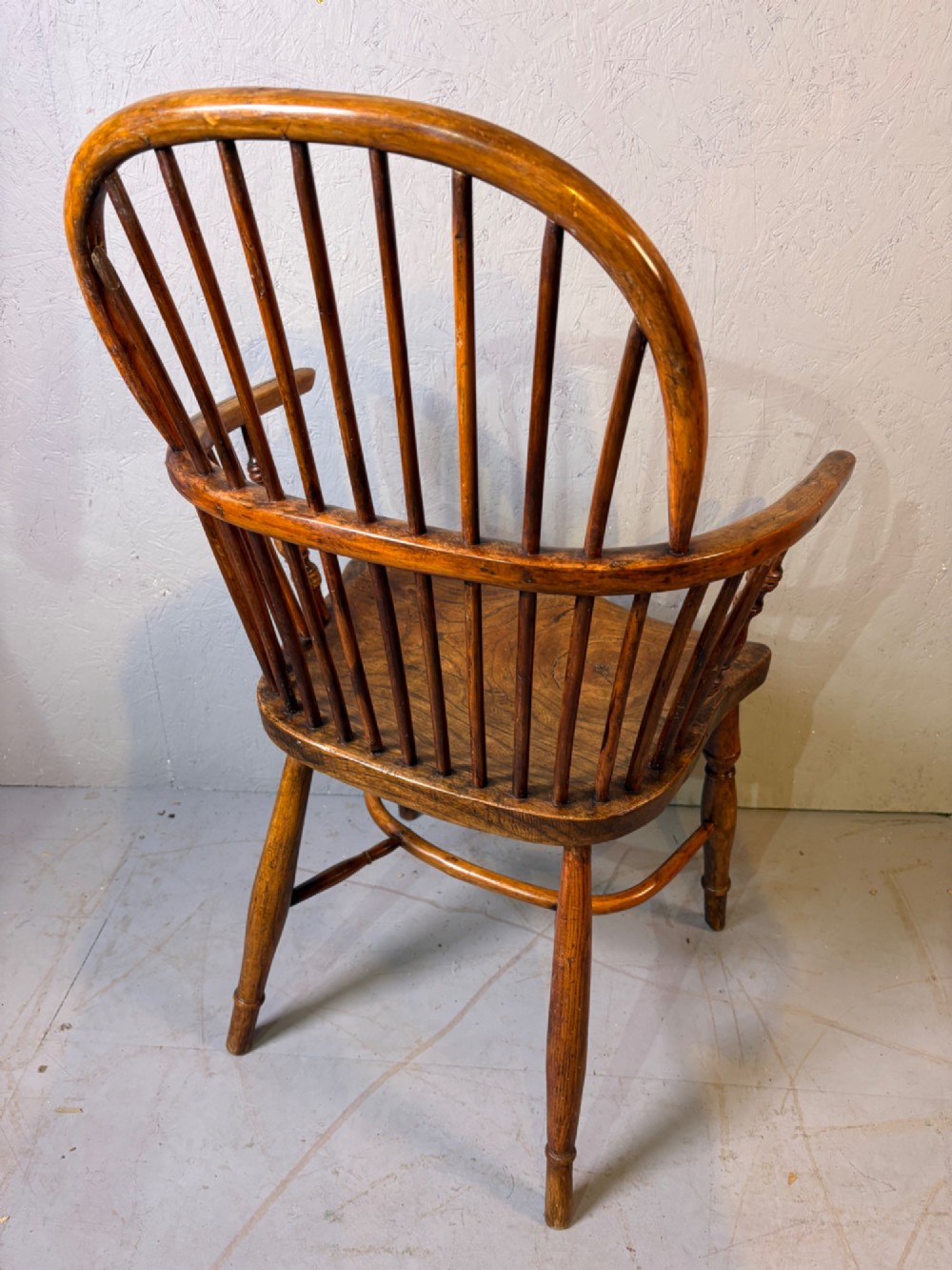 An antique Georgian fruitwood Windsor armchair featuring a arched stick back, turned arm supports, and a contoured solid wood saddle seat. View IV