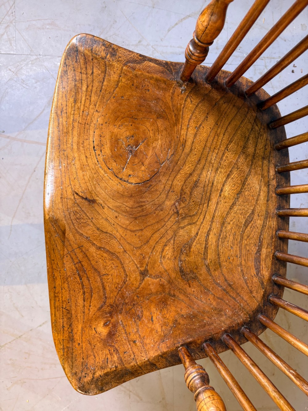 An antique Georgian fruitwood Windsor armchair featuring a arched stick back, turned arm supports, and a contoured solid wood saddle seat. View VI