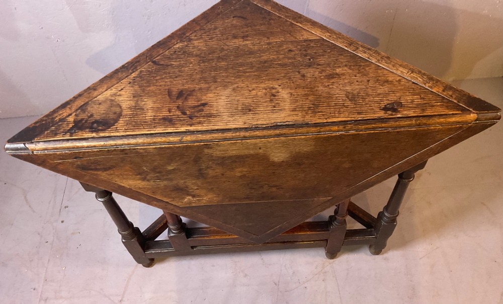 A 17th-century oak credence table featuring a triangular folding top resting on a framework with turned legs and low stretchers. View II