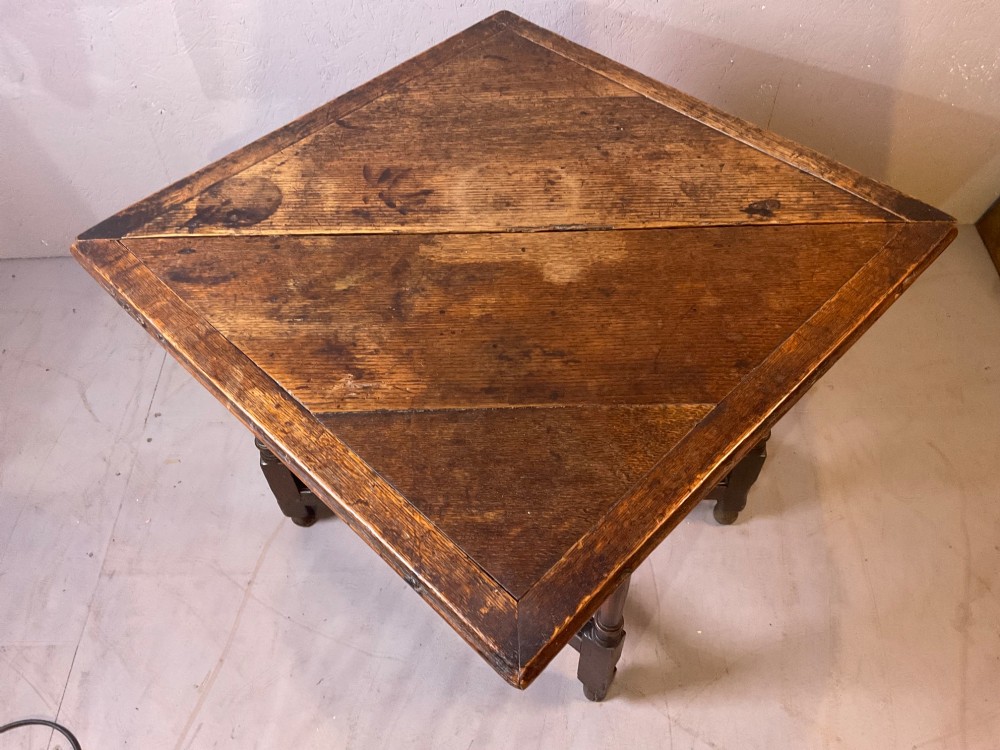 A 17th-century oak credence table featuring a triangular folding top resting on a framework with turned legs and low stretchers. View III