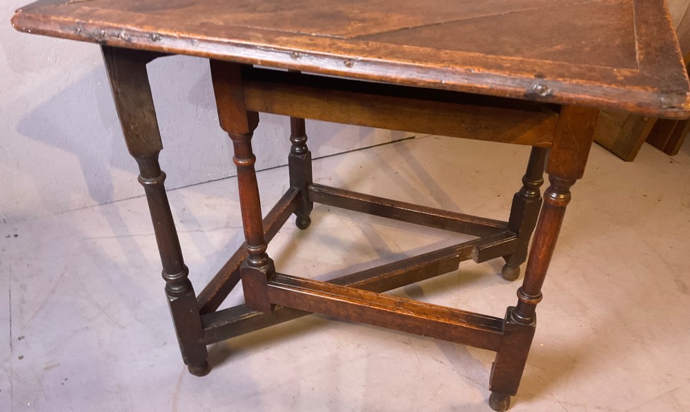 A 17th-century oak credence table featuring a triangular folding top resting on a framework with turned legs and low stretchers. View VI
